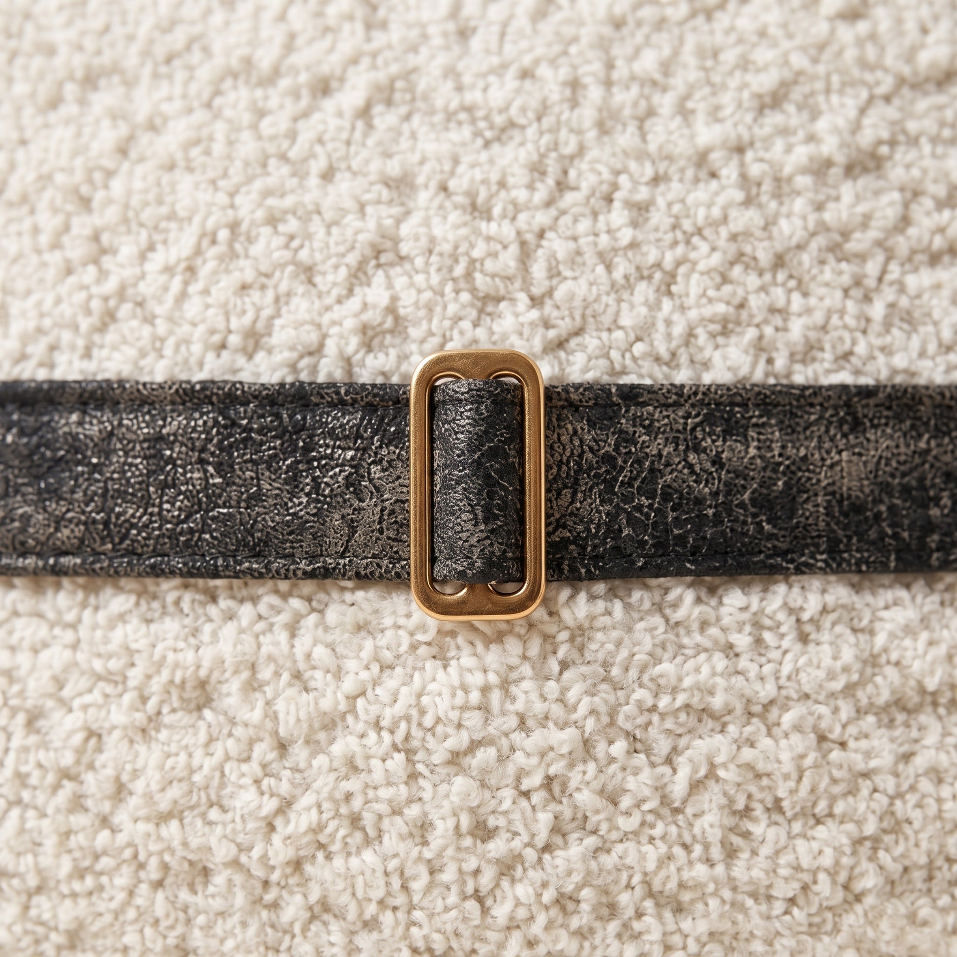 Close-up of Dream Cloud ivory texture, black trim and bronze buckle
