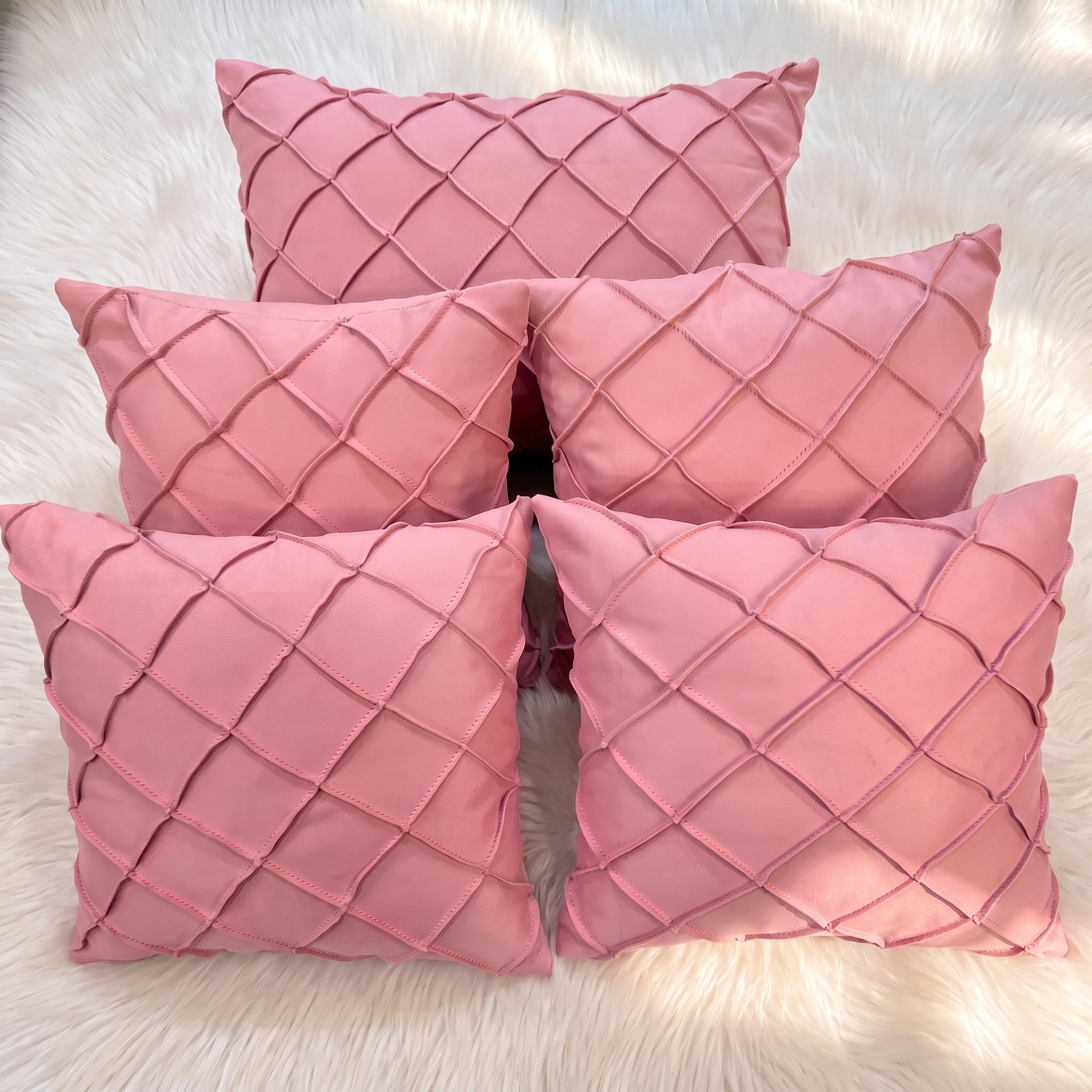 Five dusty rose velvet pillow covers arranged together, featuring raised handwoven geometric diamond lattice detailing.