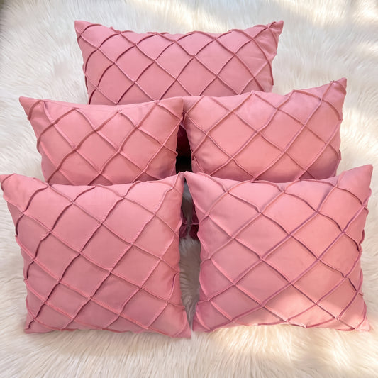 Five dusty rose velvet pillow covers arranged together, featuring raised handwoven geometric diamond lattice detailing.