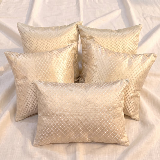 Five champagne-gold jacquard pillow covers arranged together, showing four square covers and one rectangular lumbar cover with a woven geometric lattice pattern.
