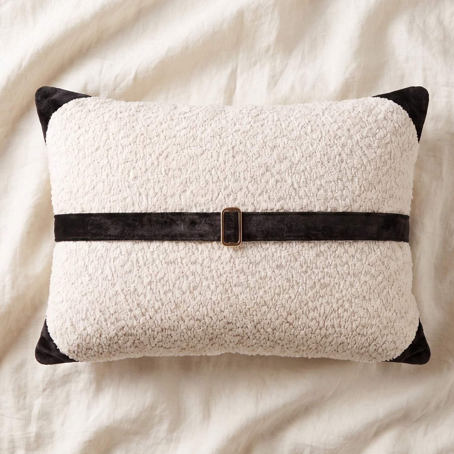 White bouclé lumbar pillow cover with black printed velvet banding, corner accents and bronze-tone buckle hardware.