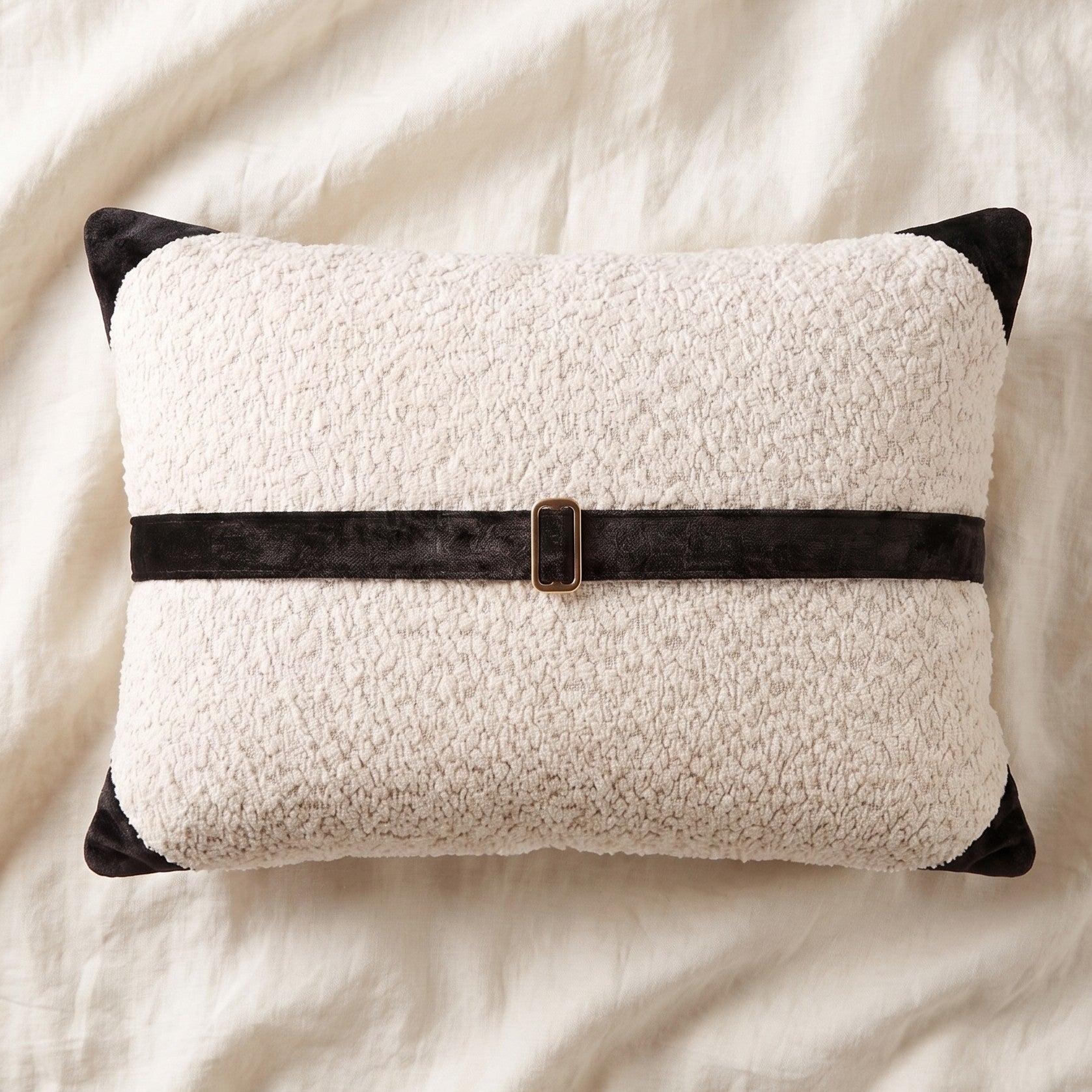 White bouclé lumbar pillow cover with black printed velvet banding, corner accents and bronze-tone buckle hardware.