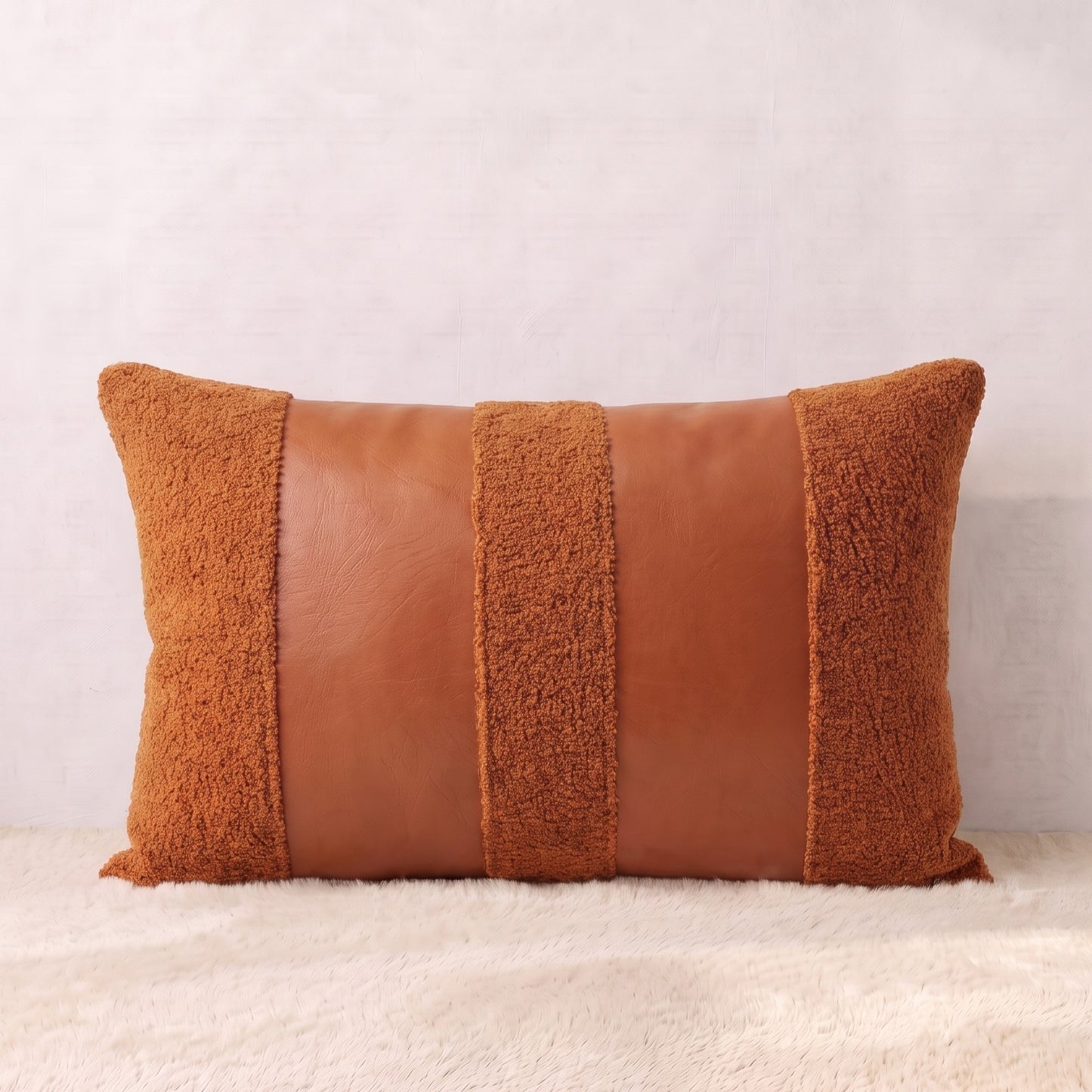 Rectangular terracotta lumbar pillow cover combining curly bouclé with smooth faux leather vertical accent panels.
