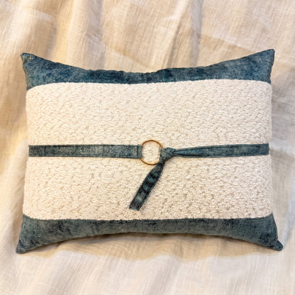 Ivory bouclé rectangular lumbar pillow cover bordered with blue-gray velvet and finished with a matching strap and gold-tone ring.
