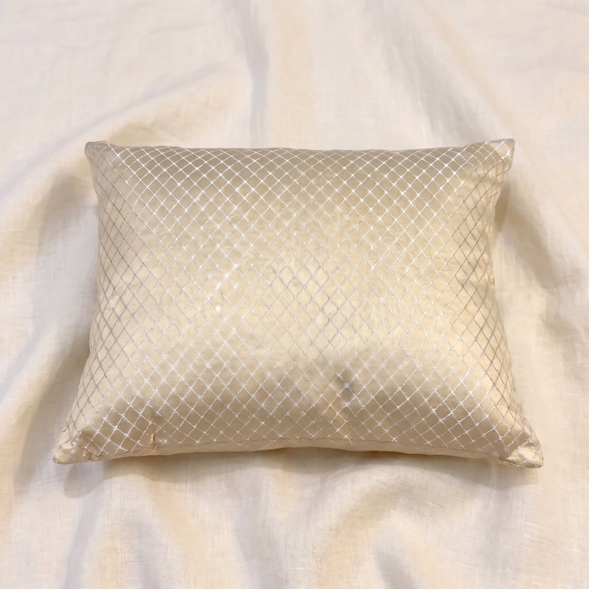 Angled view of a champagne-gold jacquard pillow cover showing the LUMBAR shape, corner construction, woven texture and subtle fabric sheen.
