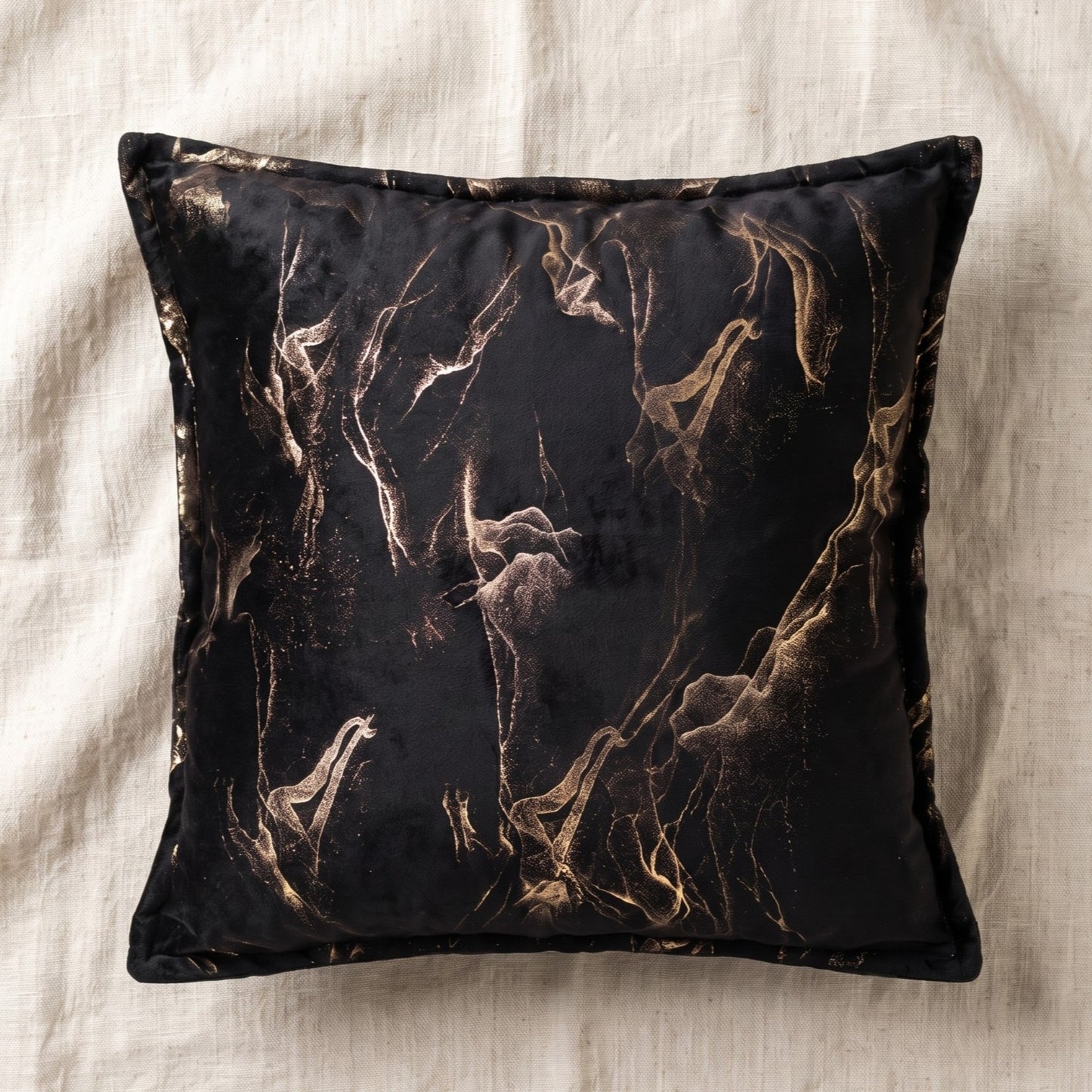 Square black printed velvet pillow cover with gold abstract smoke pattern and coordinating edge detailing.
