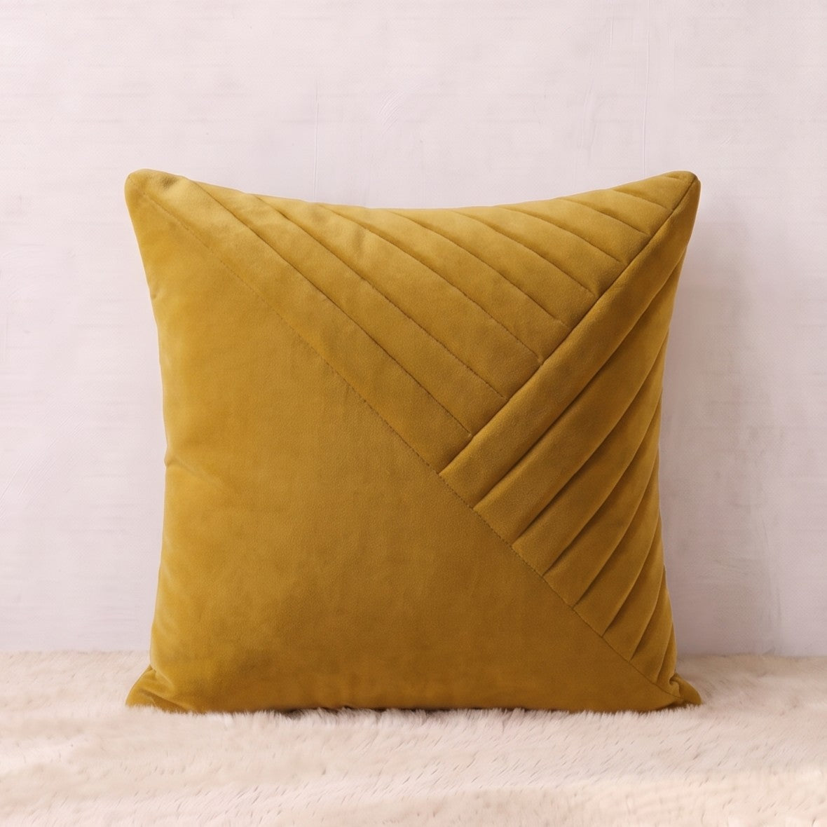 Mustard-gold square velvet pillow cover with layered diagonal pleated panels forming a geometric design.