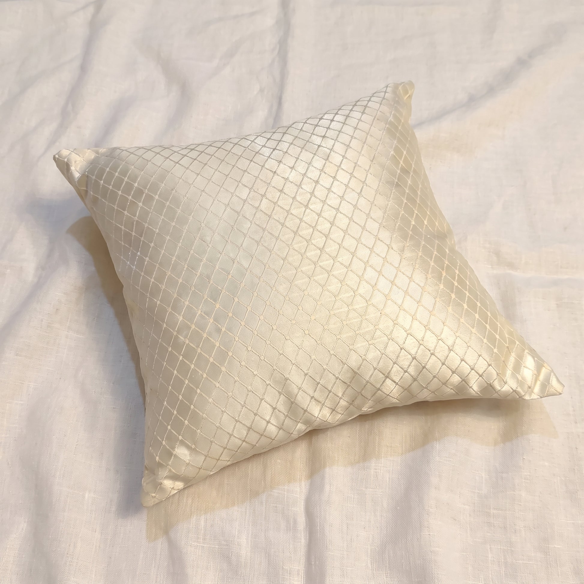Square champagne-gold jacquard pillow cover with an all-over woven geometric diamond lattice pattern and softly reflective finish.
