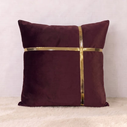 Square burgundy velvet pillow cover with horizontal and vertical reflective gold-tone trim forming a geometric cross design.
