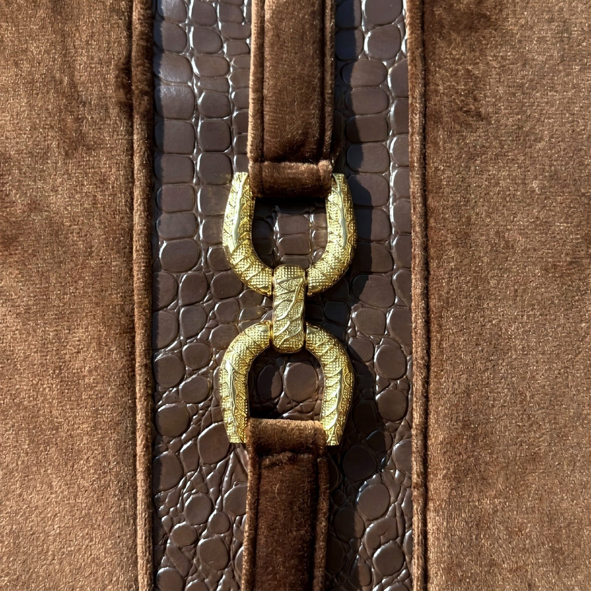 Close-up of Mocha Crest gold-tone decorative hardware and dark brown croc-embossed faux leather