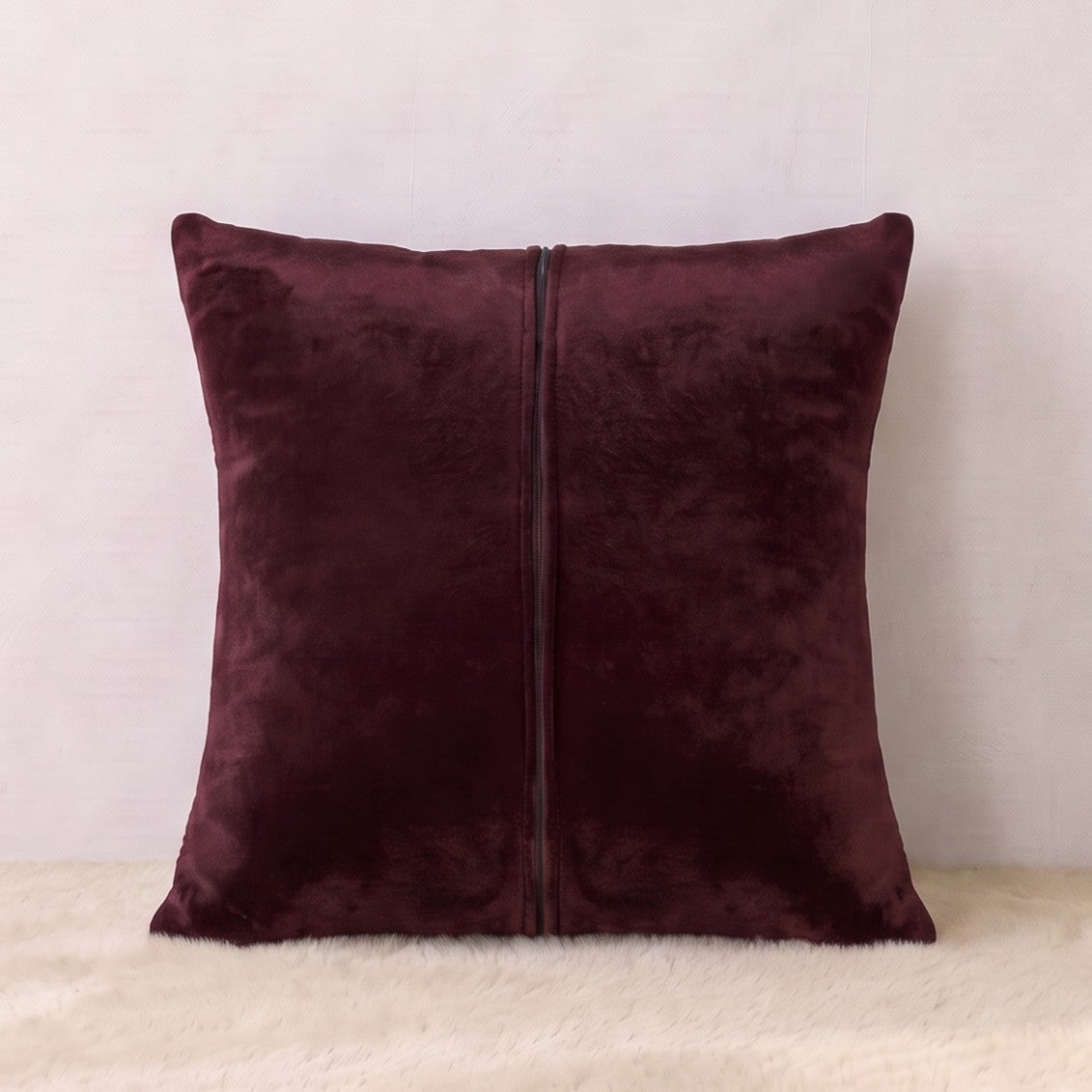 Back of a burgundy velvet square pillow cover showing the matching velvet reverse and zipper closure.
