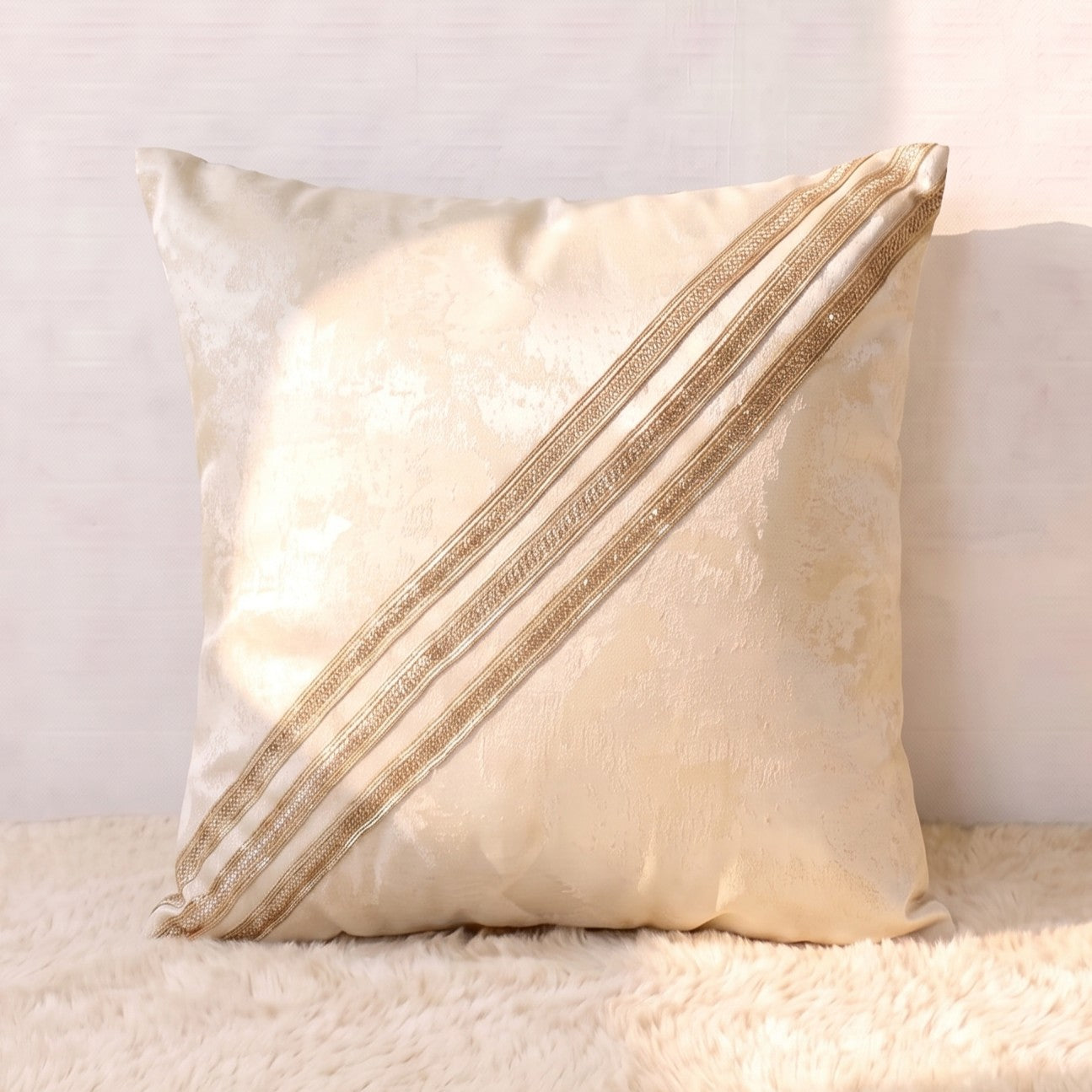 Champagne-gold jacquard square pillow cover with three diagonal decorative gold lace bands across the front.
