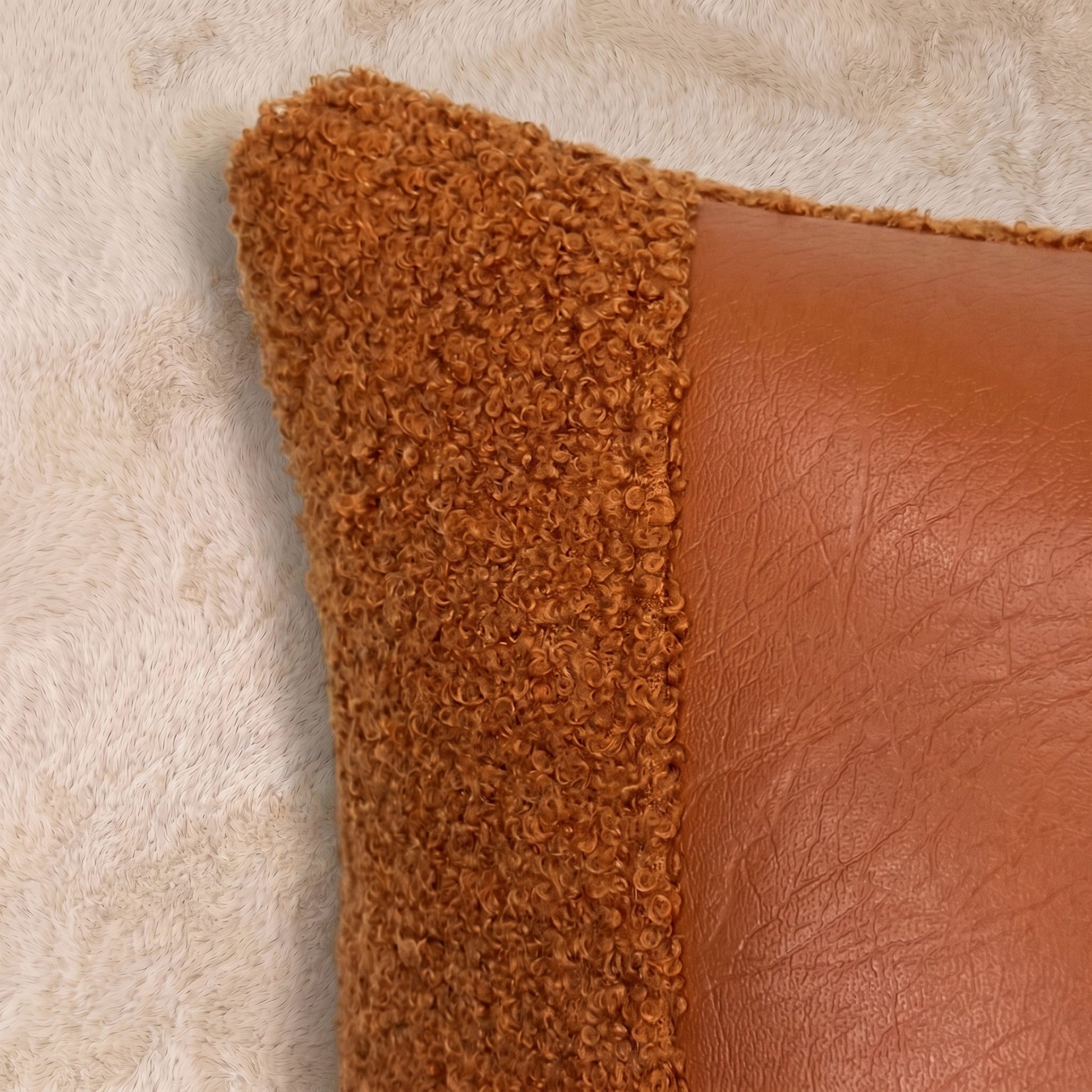 Close-up of terracotta curly bouclé beside smooth faux leather, showing contrasting textures, stitching and warm orange-brown tones.