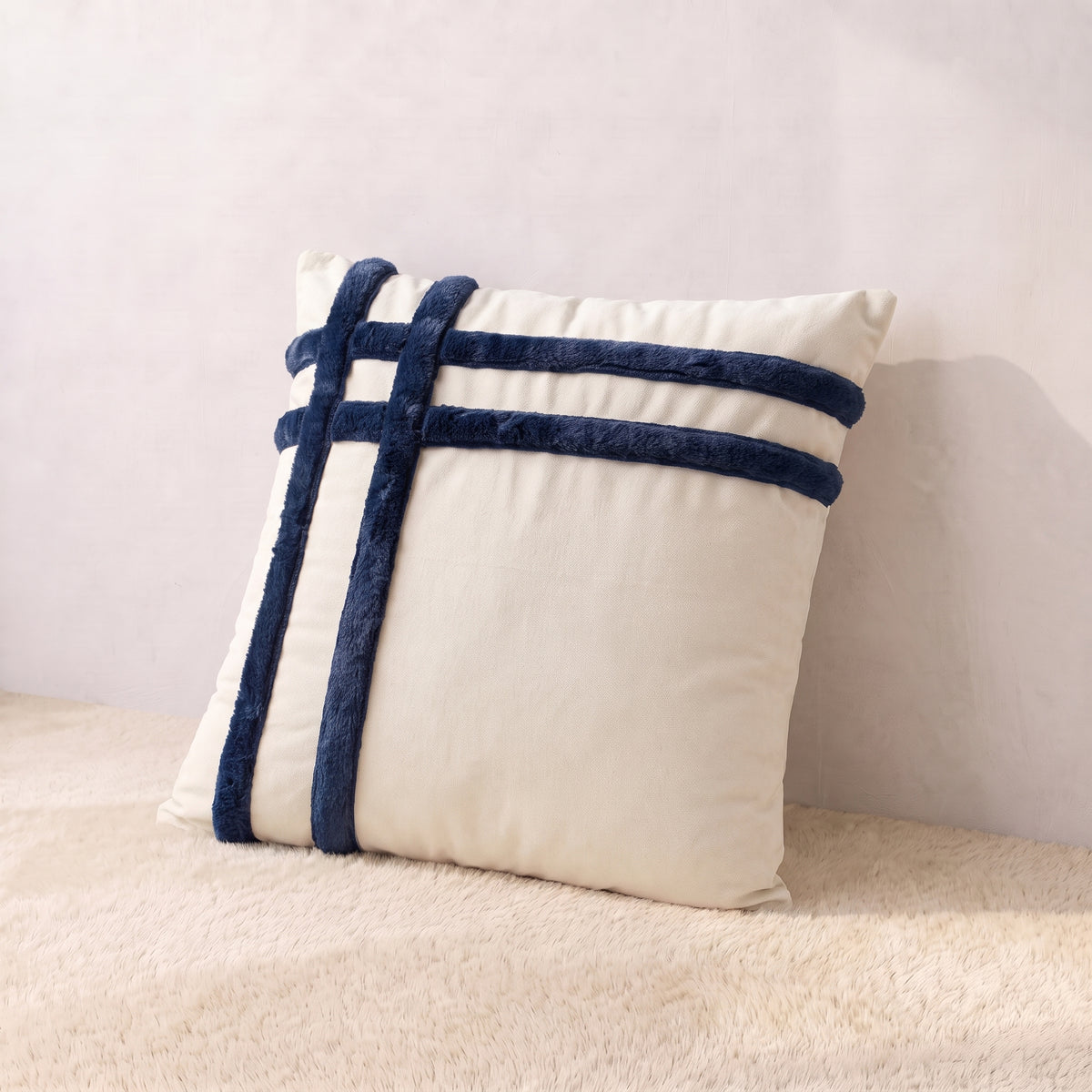 Ivory velvet square pillow cover with intersecting navy corduroy horizontal and vertical decorative bands.
