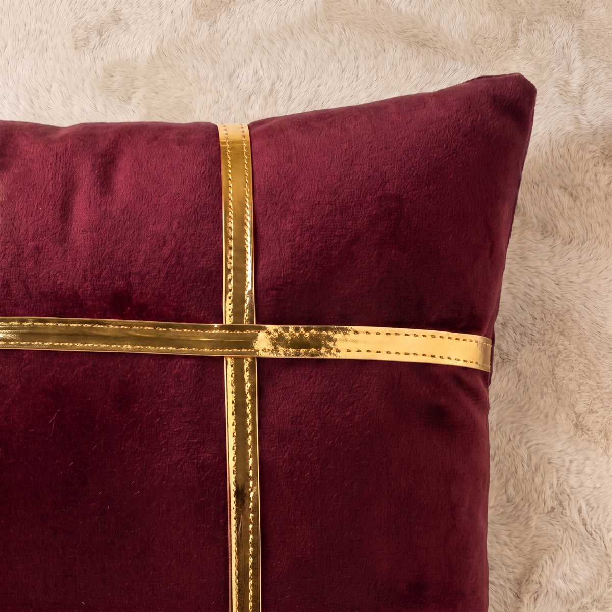 Close-up of soft burgundy velvet beside reflective gold-tone decorative trim, showing fabric texture, stitching and surface finish.
