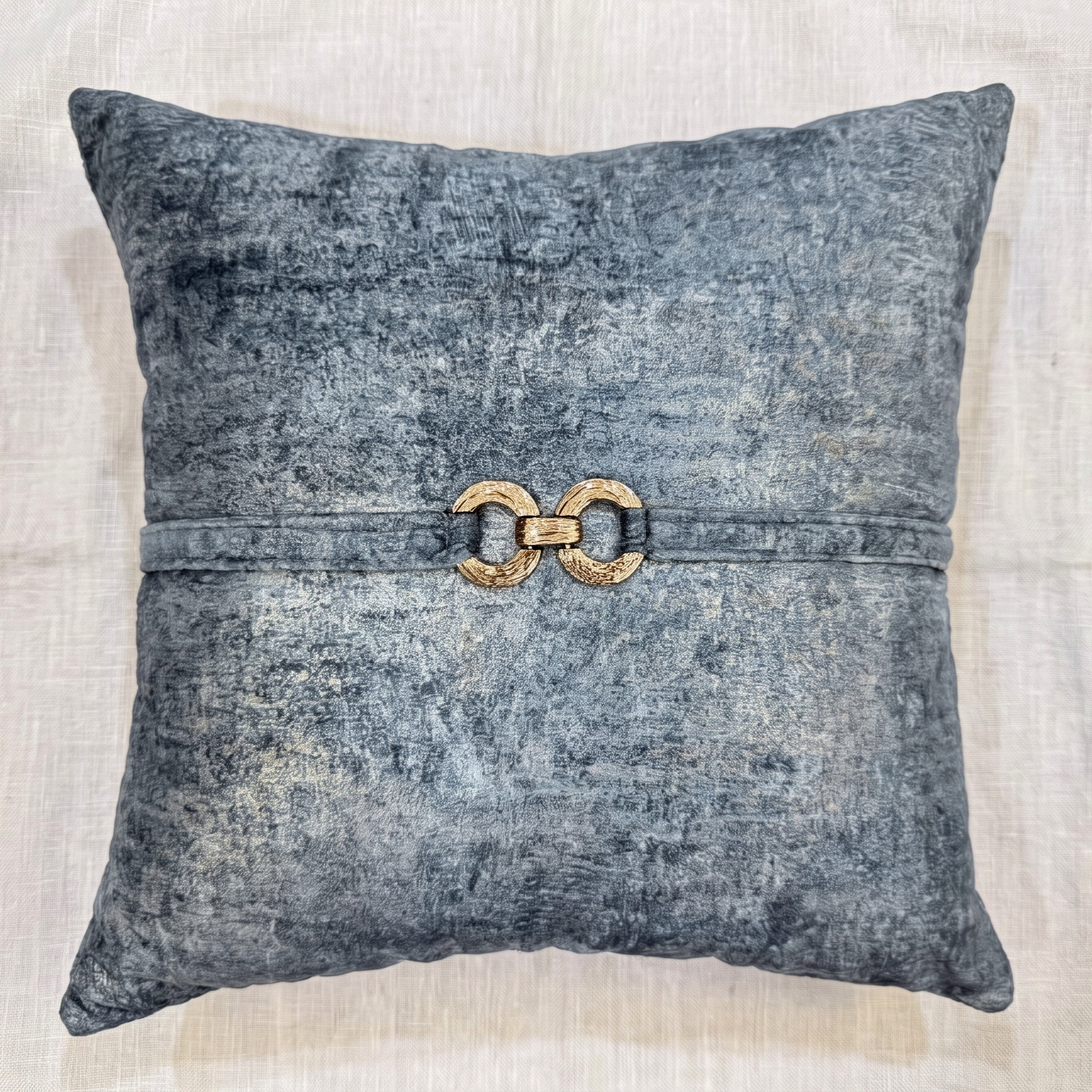 Blue-gray velvet square pillow cover with a matching velvet strap and decorative gold-tone double-ring hardware.