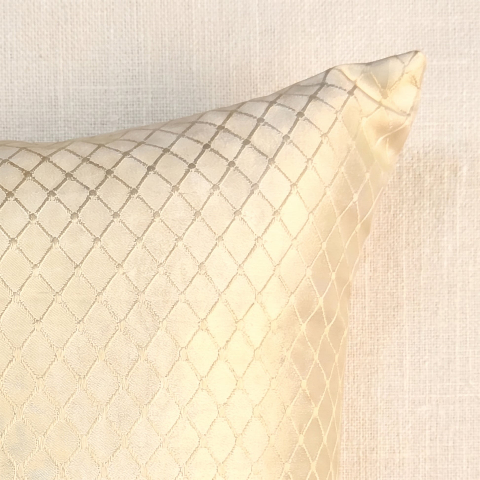 Close-up of champagne-gold jacquard fabric showing the woven geometric lattice pattern, reflective threads and detailed surface texture.
